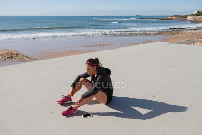 Young woman sitting by beach, Carcavelos, Lisboa, Portugal, Europe — Stock Photo