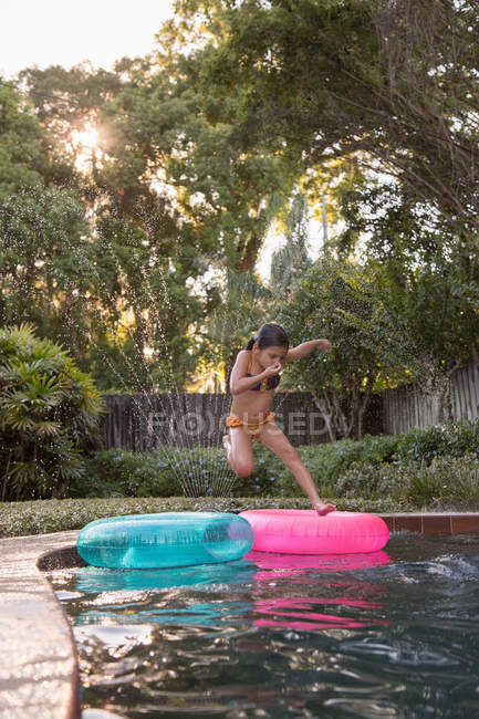 Young girl jumping in outdoor swimming pool — Stock Photo