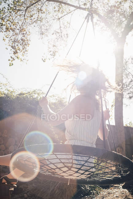 Junge Frau schaukelt auf Gartenschaukel — Stockfoto