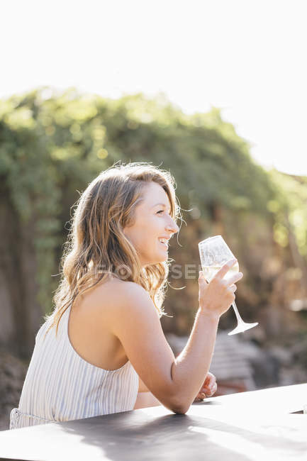 Молодая женщина на улице пьет из бокала вина — стоковое фото
