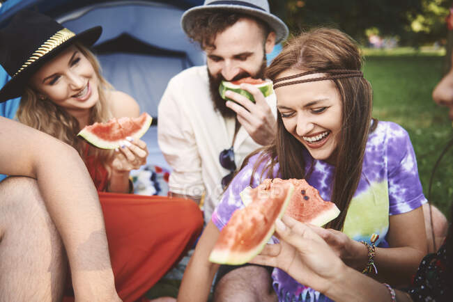 Giovani amici adulti boho mangiare fette di melone al festival — Foto stock