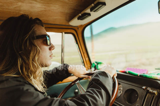 Cheveux longs jeune homme conduisant un véhicule vintage — Photo de stock
