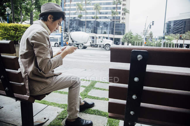 Молодий чоловік, за допомогою смартфона на лавці — стокове фото