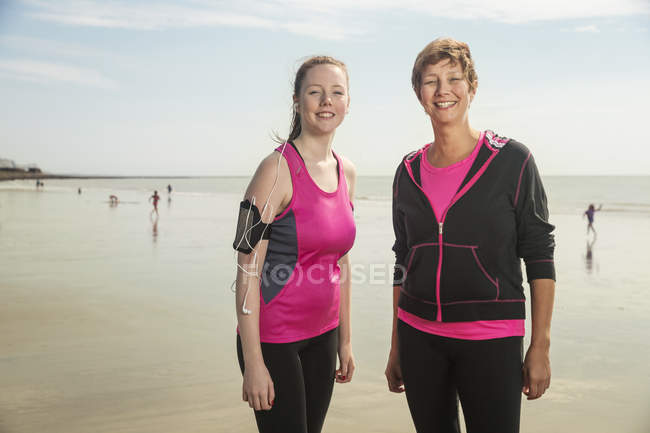 Mãe e filha na praia sorrindo para a câmera — Fotografia de Stock