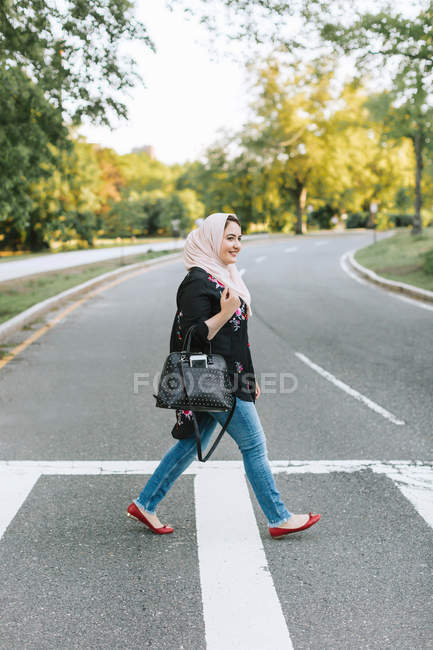Молодая женщина в хиджабе переходит дорогу — стоковое фото