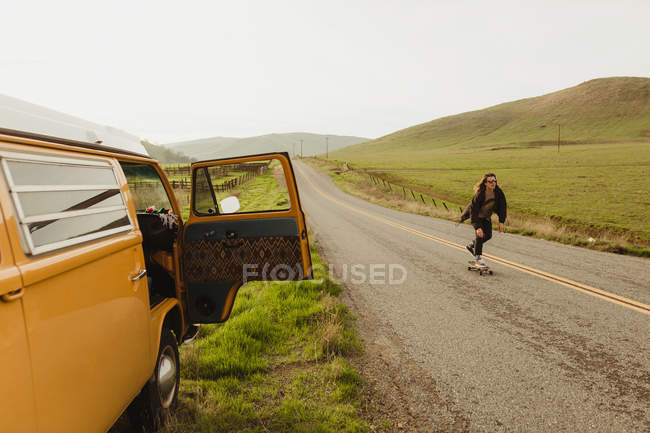 Молодой мужчина катается на скейтборде по сельской дороге, Эксетер, Калифорния, США — стоковое фото