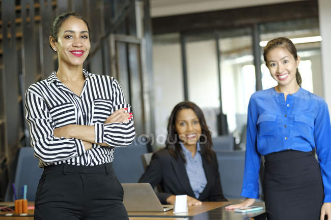 Porträt von drei Geschäftsfrauen im Großraumbüro, die in die Kamera lächeln — Stockfoto