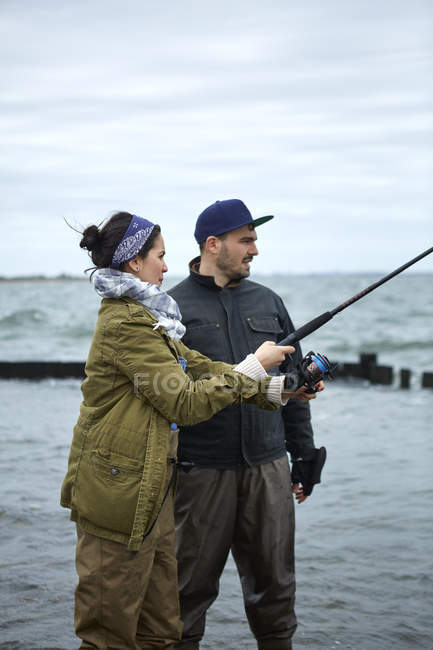 Молодой человек учит девушку рыбалке — стоковое фото