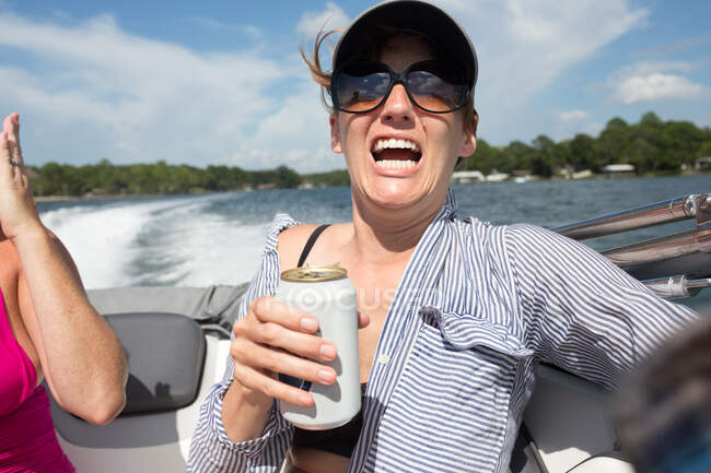 Женщина на катере, держит пиво, шокированное выражение лица — стоковое фото