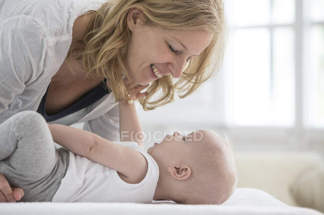 Menino deitado na cama cara a cara com a mãe — Fotografia de Stock