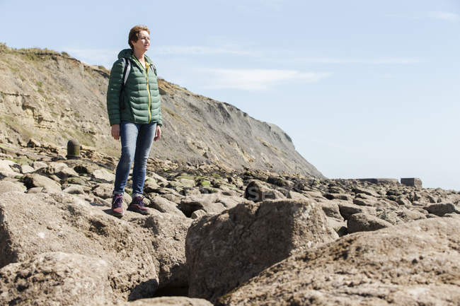 Жінка на кам'янистому узбережжі дивиться на море — стокове фото