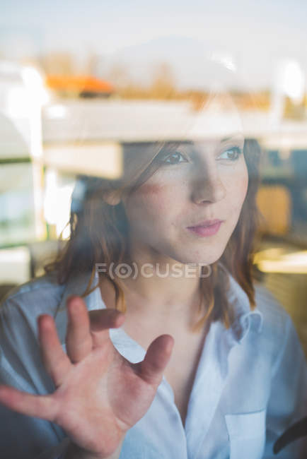 Portrait de jeune femme regardant par la fenêtre — Photo de stock