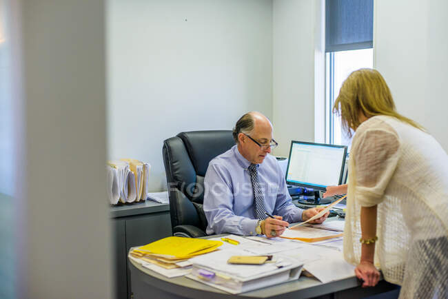 Старший человек обсуждает бумажную работу с офисным работником в офисе — стоковое фото