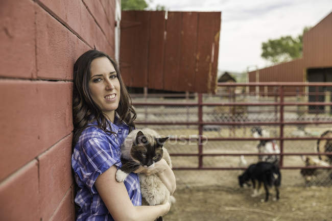 Portrait of young woman holding cat on ranch, Bridger, Montana, USA — Stock Photo