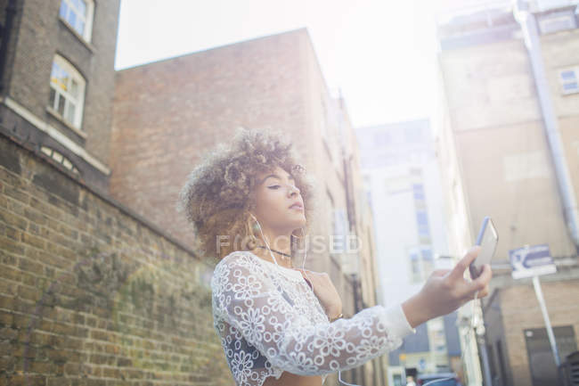 Low angle view Young woman taking selfie on smartphone — Stock Photo