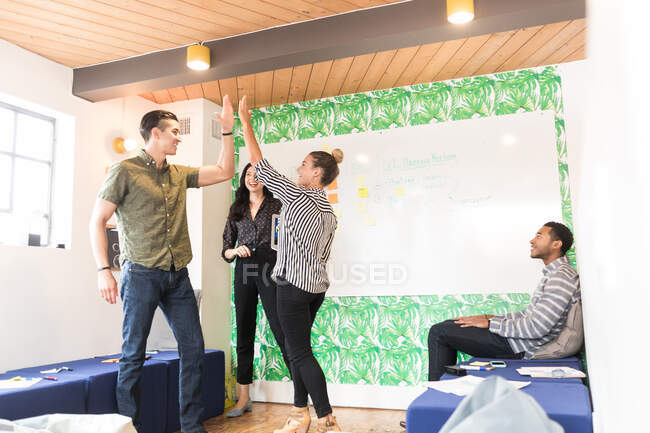 Grupo de empresários e mulheres fiving alta na sala de reuniões criativas — Fotografia de Stock