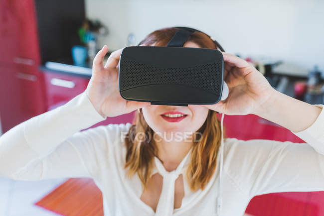 Ritratto di giovane donna in cucina guardando attraverso cuffie realtà virtuale — Foto stock