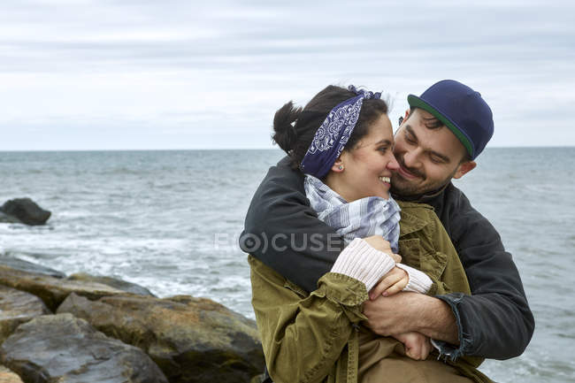 Jovem casal abraçando na praia rochosa — Fotografia de Stock