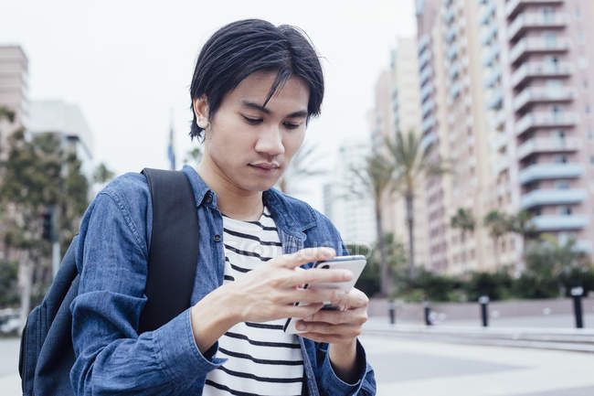 Young man using smartphone outdoors — Stock Photo