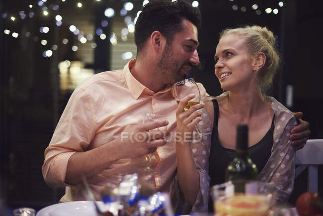 Пара сидящих за столом, держащих бокалы с вином, лицом к лицу, улыбающихся — стоковое фото
