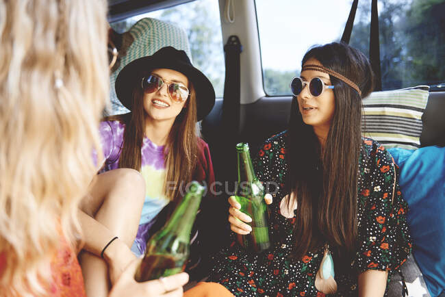 Tres mujeres jóvenes boho relajándose en furgoneta recreativa - foto de stock