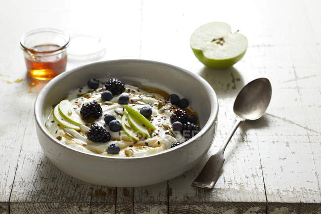 Greek yogurt with apple, blackberries, blue berries and honey — Stock Photo