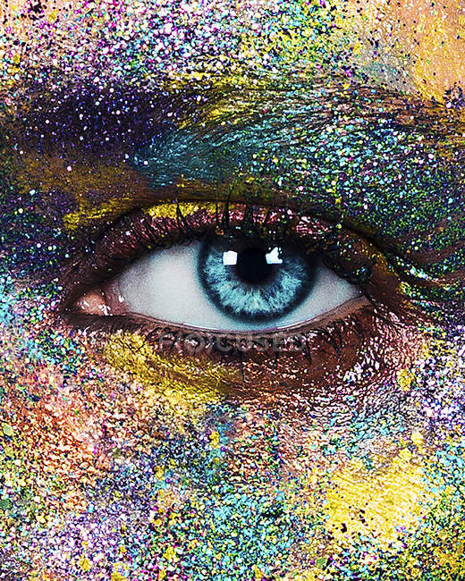 Femme aux yeux bleus avec de la poudre de couleur pailletée sur le visage — Photo de stock