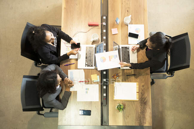Drei Geschäftsfrauen am Schreibtisch, Laptop, Blick aufs Smartphone, Blick über den Kopf — Stockfoto