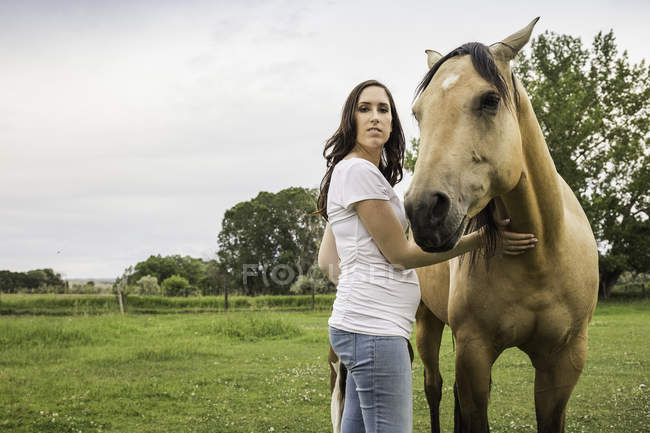 Portrait de jeune femme debout avec cheval — Photo de stock