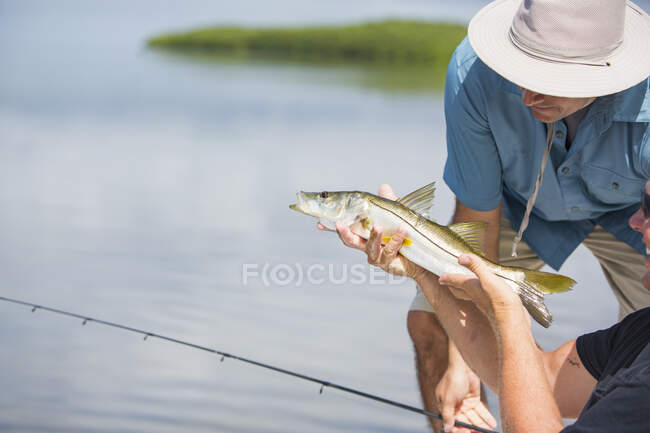 Homens admirando peixe ronco antes de liberá-lo — Fotografia de Stock