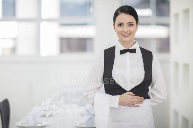 Retrato de camarera cerca de mesa servida en restaurante - foto de stock