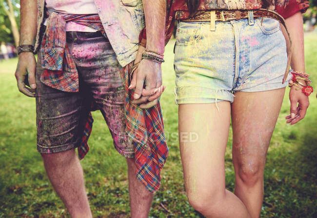 Waist down view of young couple covered in coloured chalk powder at festival — Stock Photo