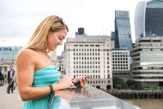 Frau steht auf Londoner Brücke und benutzt Smartphone — Stockfoto