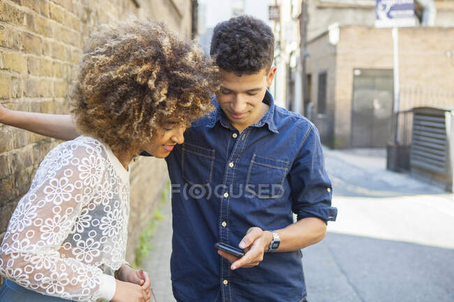 Jeune couple dans la rue, regardant smartphone — Photo de stock