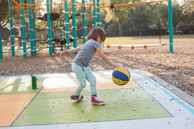 Little Girl bouncing ball in playground at daytime — Stock Photo