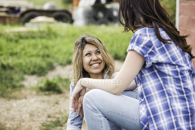 Дві молоді жінки в розмові посміхаються на відкритому повітрі — стокове фото