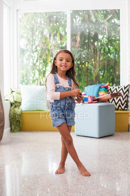 Портрет дівчини у вітальні, що тримає іграшкову камеру — стокове фото
