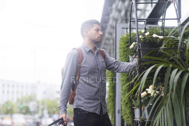 Man looking at plants on shelf outdoors — Stock Photo