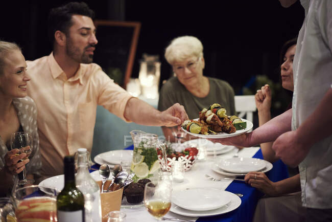 Группа людей, сидящих за столом и наслаждающихся едой — стоковое фото