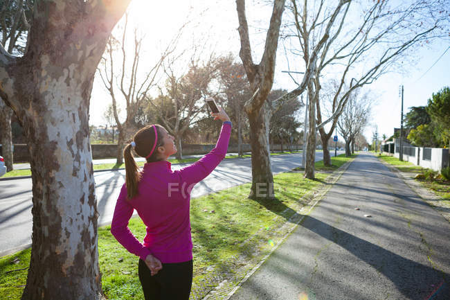 Visão traseira da mulher tomando selfie na rua — Fotografia de Stock