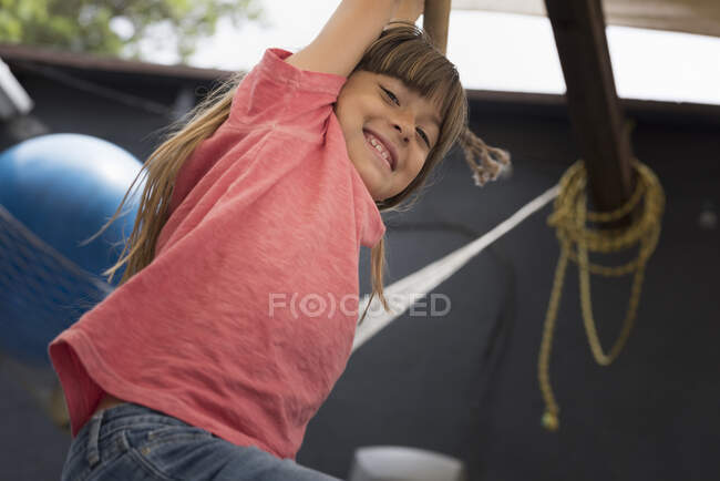Mädchen hängt an Affenstange und blickt lächelnd in die Kamera — Stockfoto