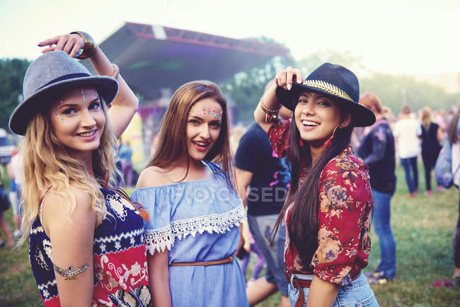 Portrait of three young female friends in trilbies at festival — Stock Photo