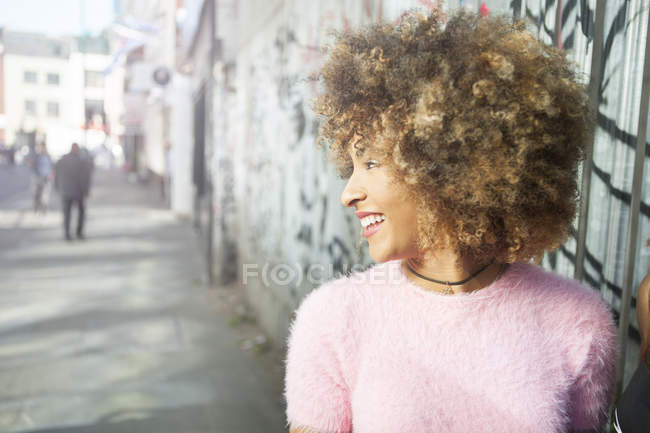 Портрет молодой улыбающейся женщины, смотрящей в сторону на городской улице — стоковое фото