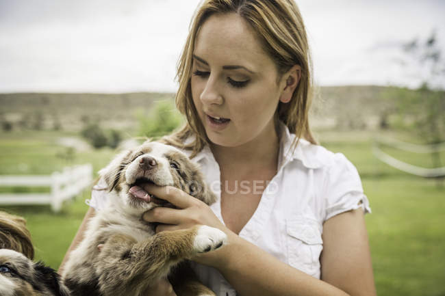 Young woman with finger in puppy's mouth on ranch, Bridger, Montana, USA — Stock Photo