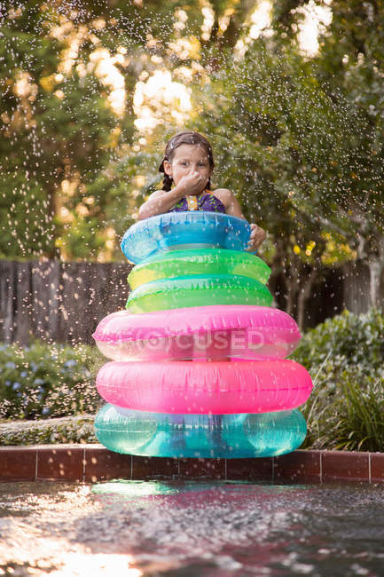 Menina em anéis infláveis que estão no lado da piscina exterior — Fotografia de Stock