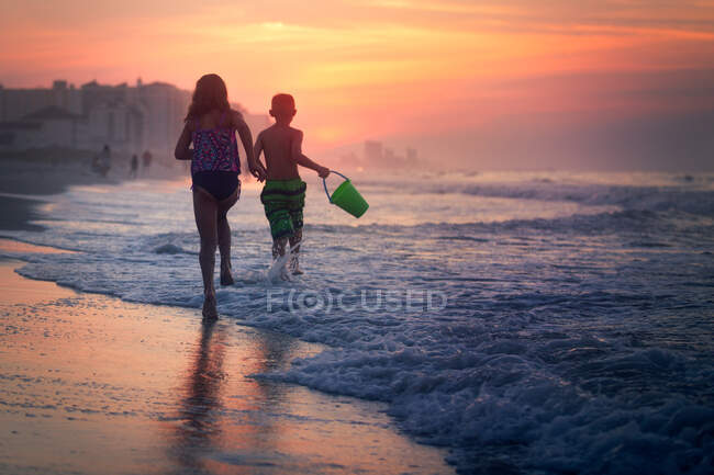 Geschwister paddeln bei Sonnenuntergang im Meer, North Myrtle Beach, South Carolina, Vereinigte Staaten — Stockfoto