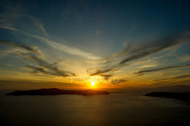 Солнце садится над морем на горизонте, Санторини, Кикладес, Греция — стоковое фото