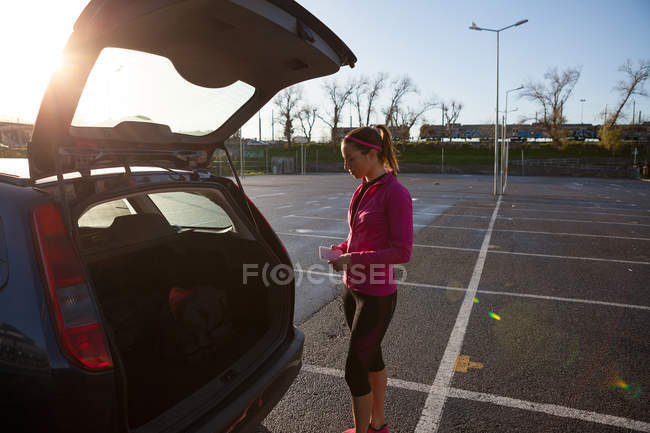 Mujer joven por baúl de coche abierto - foto de stock