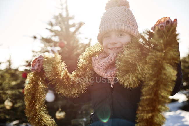 Menina na floresta de árvore de natal vestindo ouropel, retrato — Fotografia de Stock