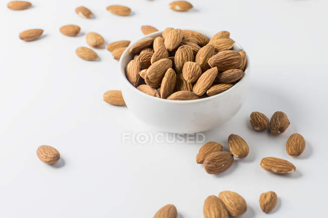 Mandelnüsse in Schüssel und auf weißem Hintergrund — Stockfoto